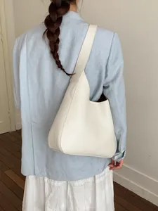 Borsa hobo minimalista in pelle bianca indossata da una modella per look da ufficio