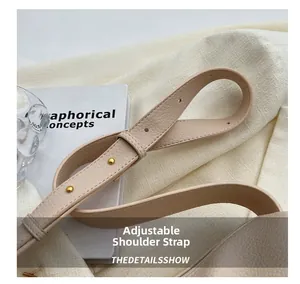 Macro shot of adjustable beige leather shoulder strap with gold circular metal buckle