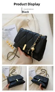 Detail of black quilted crossbody bag with gold chain strap and metal ball accessory
