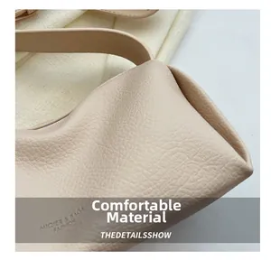 Detail shot of beige litchi grain leather texture and brand logo on the handbag
