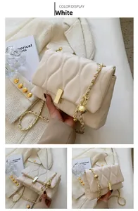 Detail view of white quilted chain bag with gold hardware and stylish metal ball strap