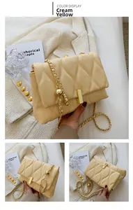 Detail of creamy yellow chain bag with wave quilting and golden ball chain strap