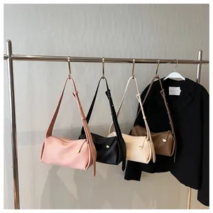 Detail of four cylinder crossbody bags in pink, black, white, and brown with wide straps