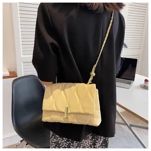 Detail of light yellow quilted chain bag with gold buckle and adjustable metal ball strap