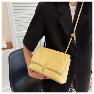 Detail of light yellow quilted chain bag with golden ball buckle and metal hardware