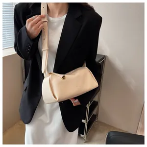 Detail view of cream leather crossbody bag with wide strap and gold geometric zipper pull