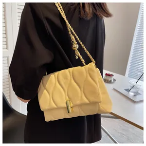 Detail of cream quilted crossbody bag with golden chain strap and wavy stitching