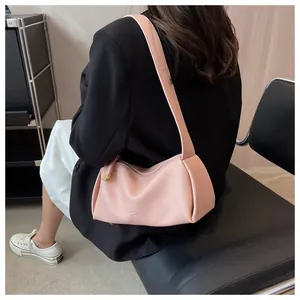 Detail of light pink textured leather underarm bag featuring golden metal zipper and wide strap