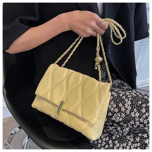 Close-up of yellow leaf-quilted crossbody bag with gold chain and metal ball detail