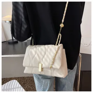 Detail of white wave-quilted leather bag with gold chain strap and metal ball decor