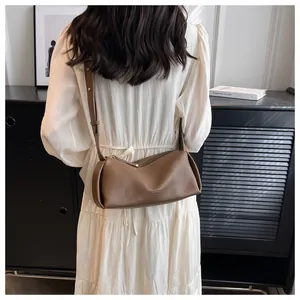 Detail of soft dark brown crossbody bag with wide strap in a minimalist interior setting