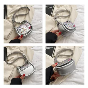 Détails d'un mini sac selle argenté avec des imprimés graffiti colorés et une bandoulière