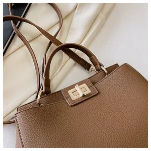 Detail of brown leather texture and gold metal twist lock on a minimalist tote bag