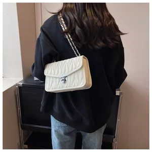 Detail of elegant V-quilted faux leather bag with silver turn-lock and chain strap