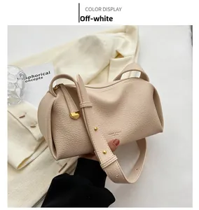 Detail view of off-white lychee texture leather bag with elegant gold zipper and brand logo