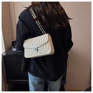 Detail of cream quilted chain bag with silver vintage clasp and leather woven strap