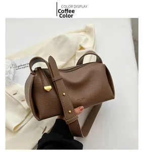 Close-up of coffee brown leather crossbody bag with wide strap and gold hardware accents