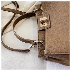 Close-up of brown litchi pattern tote bag with gold metal clasp and leather texture