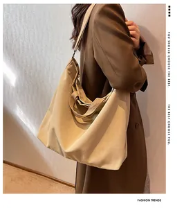 Detailed side view of a large khaki canvas tote bag worn by a model in a casual style