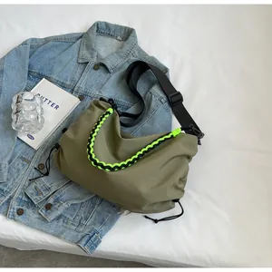 Detail of olive green nylon bag with braided rope handle and drawstring on denim