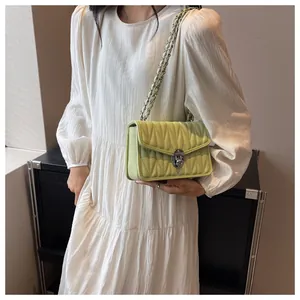 Detail of light green quilted shoulder bag with silver turn-lock and chain strap