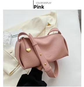 Detailed shot of pink crossbody bag with pebbled texture and gold metal studs