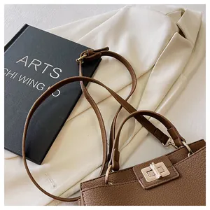 Detail of brown litchi pattern handbag featuring elegant gold metal twist lock closure