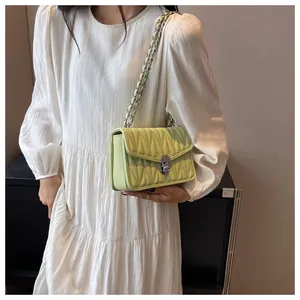 Detail of light green quilted crossbody bag with silver chain strap and twist-lock clasp