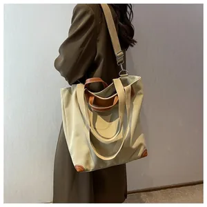 Detail of canvas tote bag showing dark brown leather handles and side reinforcement
