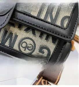 Macro detail of beige canvas crossbody bag with dark monogram and brown woven strap