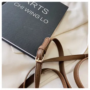 Detail of adjustable dark brown pebble leather shoulder strap with gold metal buckle