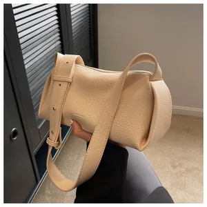 Detail view of beige lychee grain leather bag with wide strap and gold hardware accents
