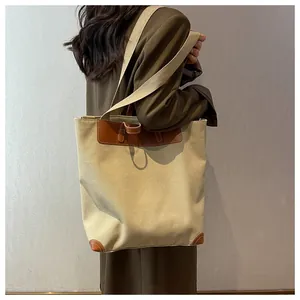 Side view of a large canvas tote bag with brown leather trim worn by a model for commuting