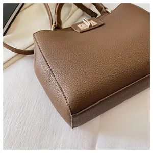 Close-up of brown litchi pattern leather handbag with gold twist lock and fine stitching