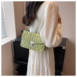 Light green quilted chain bag shown from a side view on a model in a white dress