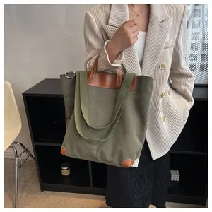 Detail of olive green canvas tote bag with brown leather reinforcement and double straps
