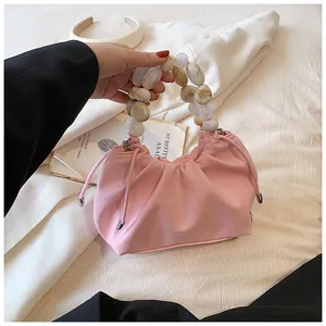 Detail of pink pleated handbag featuring decorative marble-patterned pearl bead handle