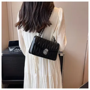 Detail showing V-shaped quilted pattern and silver swivel lock on black crossbody bag