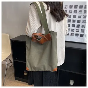 Detail view of army green canvas tote with brown leather handles and a fabric shoulder strap