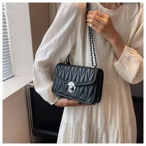 Detail view of a black matelassé shoulder bag with silver chain strap and metallic lock
