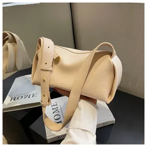 Detail of beige litchi grain texture bag with golden buckle and wide shoulder strap