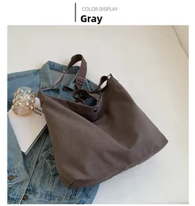 Detail shot of grey canvas tote bag with adjustable brown strap and metallic buckle