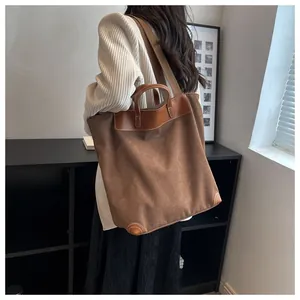 Detailed view of a large brown canvas tote bag with leather straps on model's shoulder