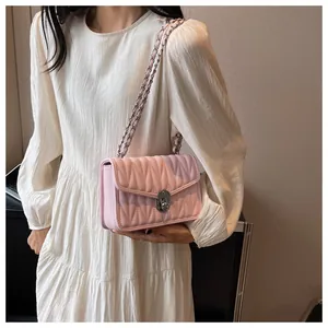 Detail of pink quilted leather bag with V-shaped stitching and silver chain strap