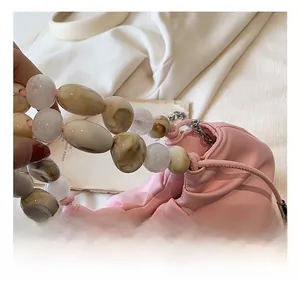 Detail of pink ruched cloud bag featuring elegant marble texture resin bead handle