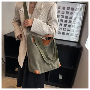 Dark green canvas tote bag with leather trim worn by a model in a vintage interior setting