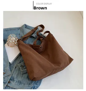 Detail view of large brown canvas tote bag featuring double handles and durable metal snap