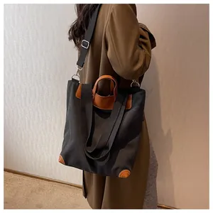 Detail of canvas tote bag showing black fabric, brown leather trim and sturdy handle