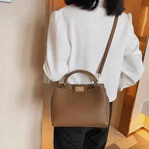 Brown lychee leather handbag with gold twist lock shown on model back view