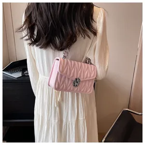 Detail of light pink quilted crossbody bag with silver chain strap and metal lock